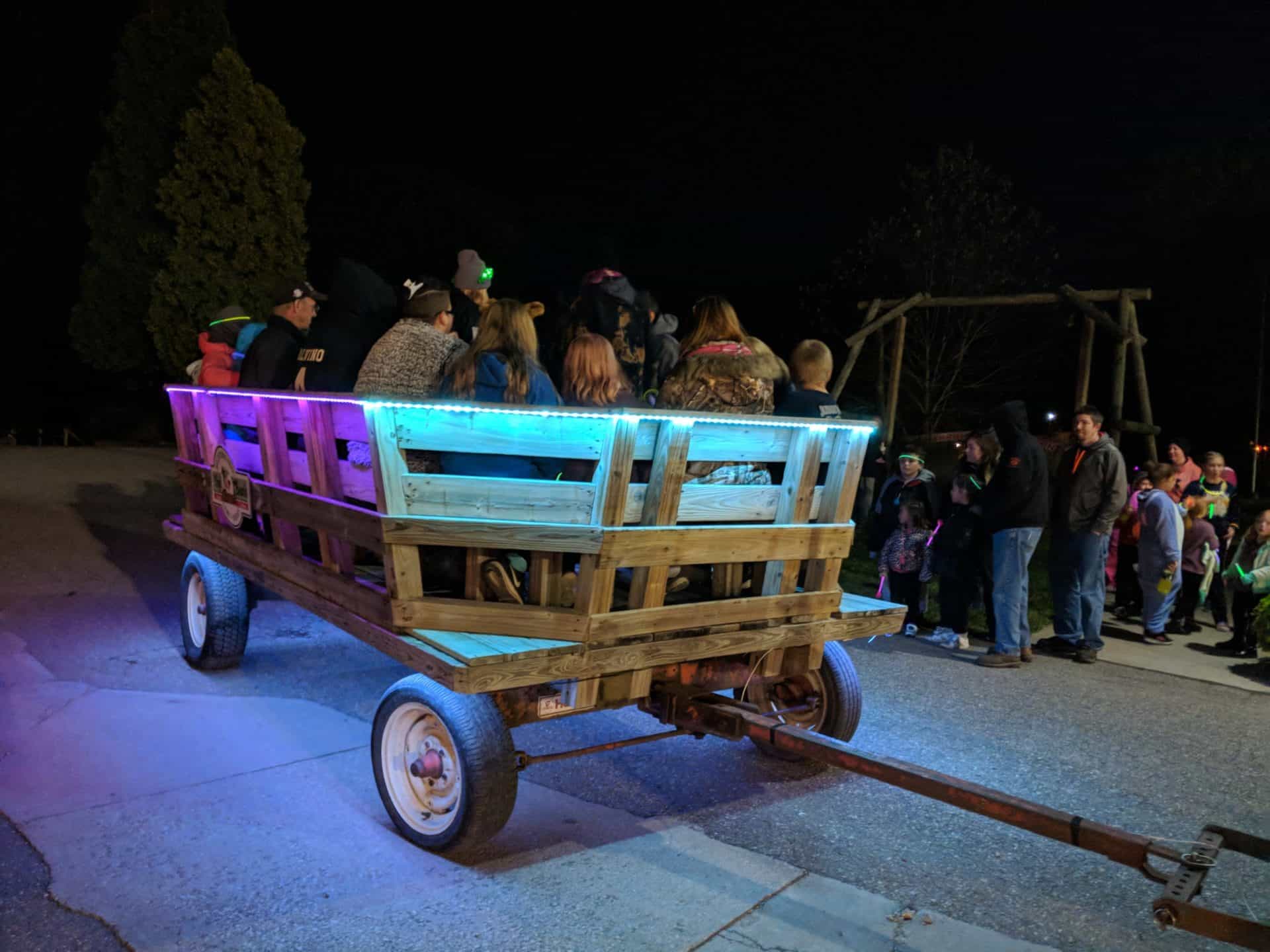 A group of people on a wooden wagon at night.
