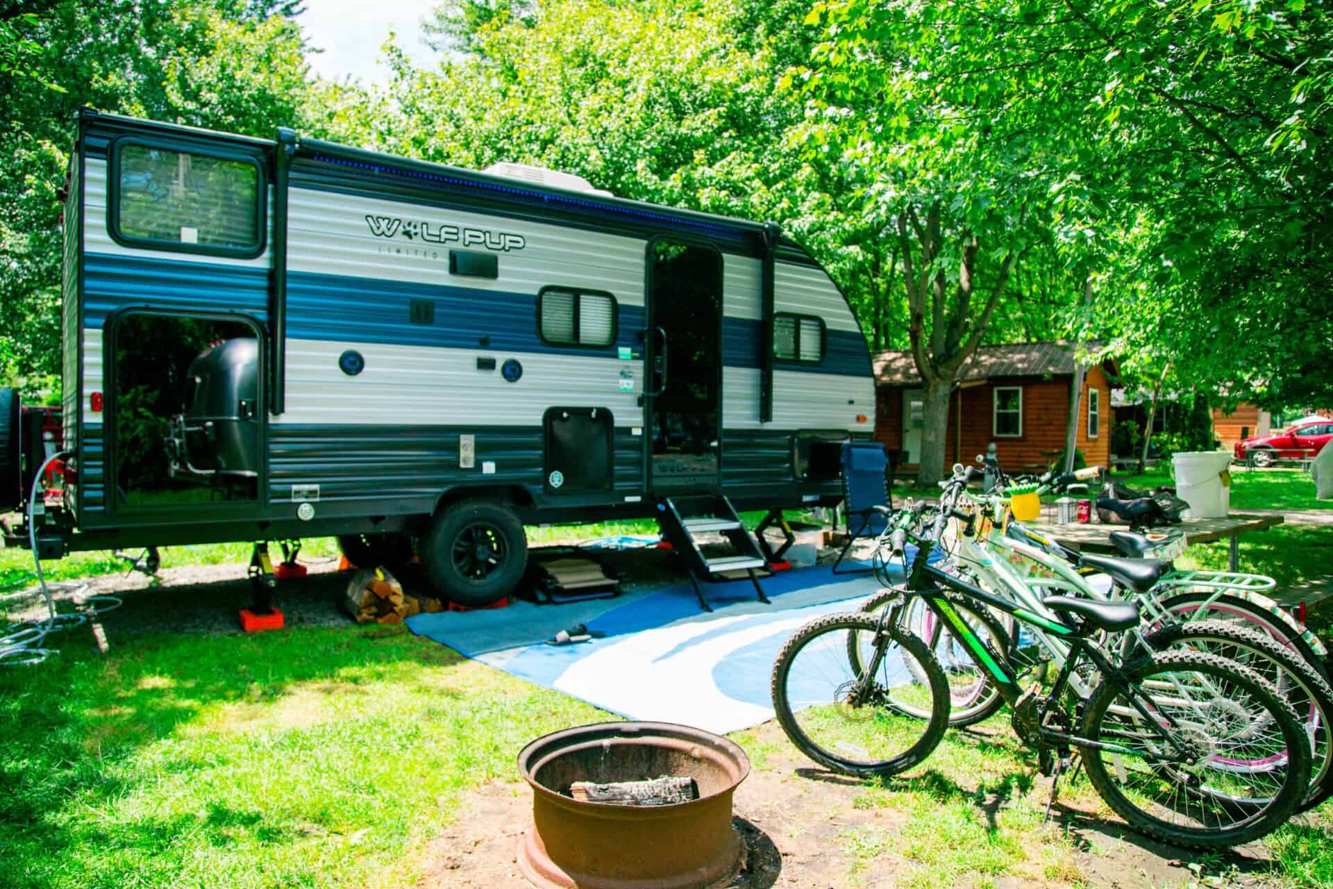An rv parked next to a fire pit and bicycles.