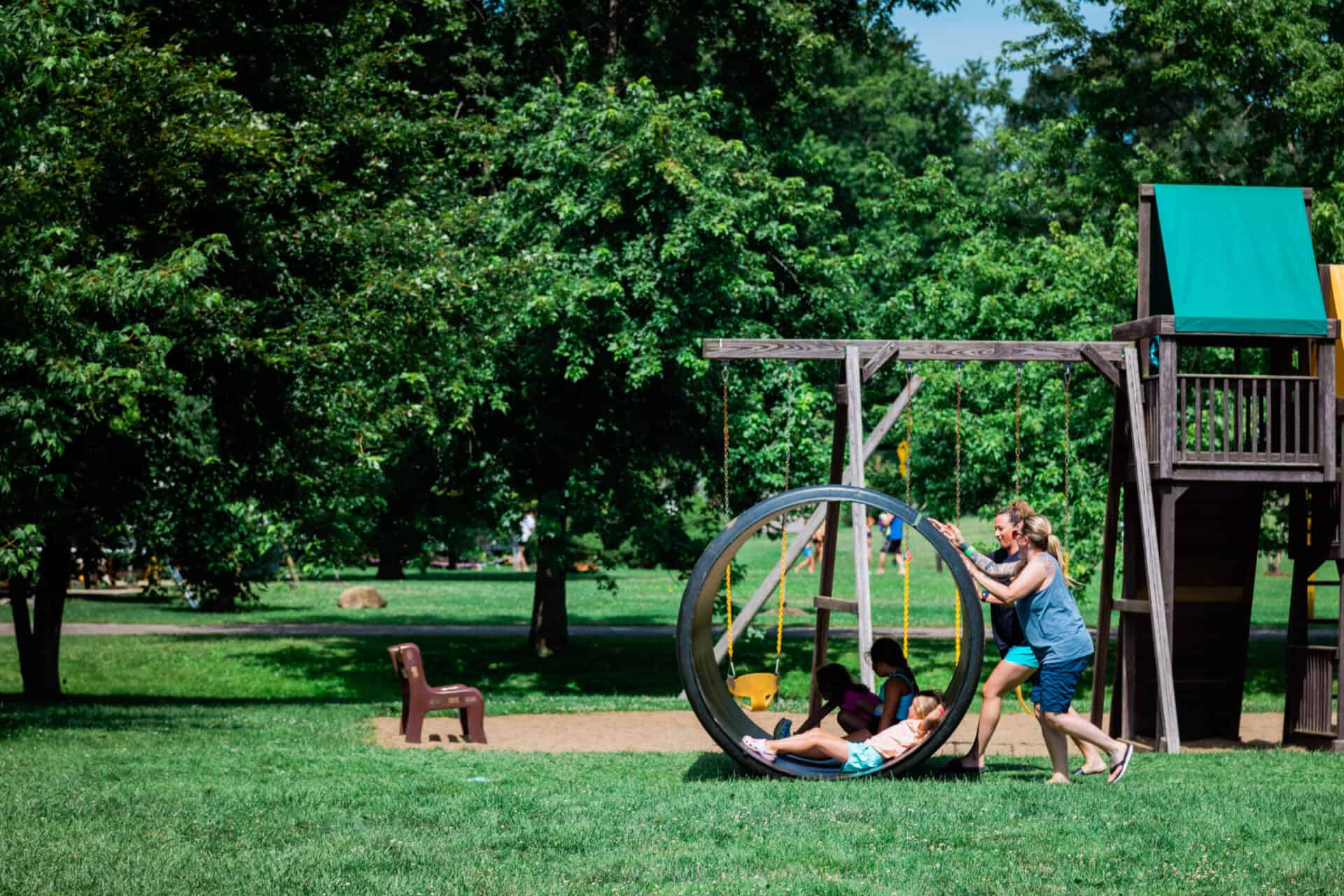 Two children engaged in activities on a swing set in a park.