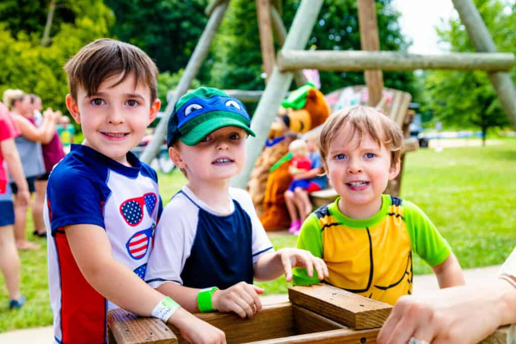 A group of children are playing with a wooden box in a playground.