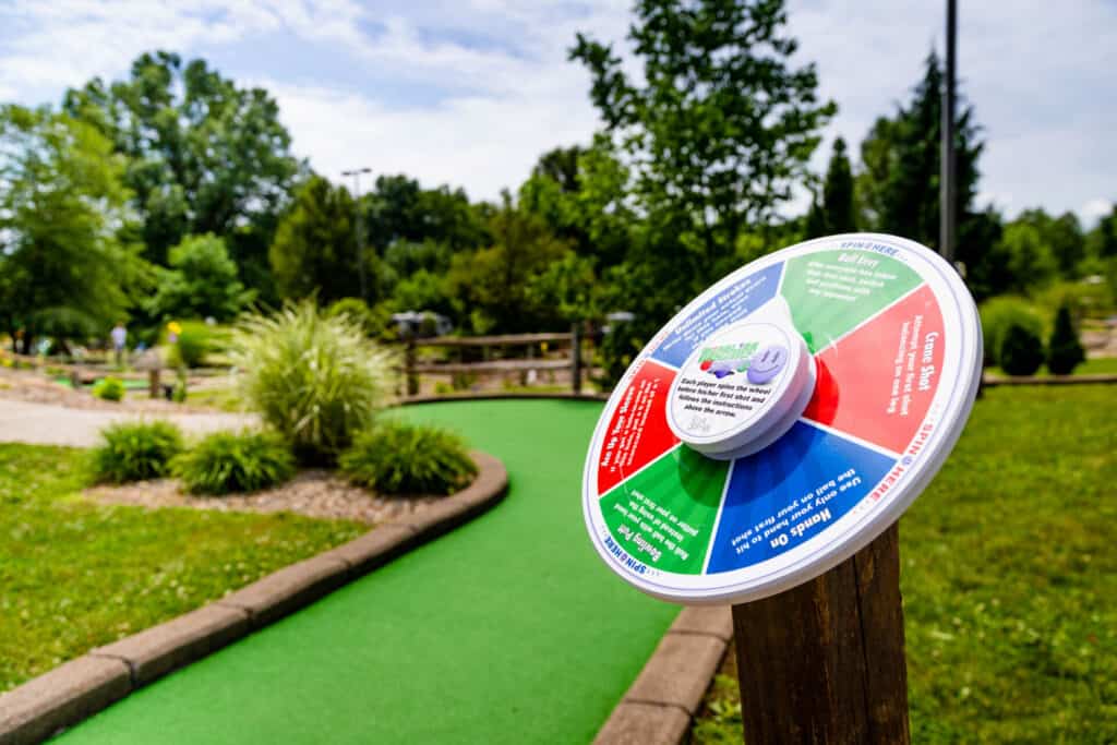 A mini golf course in a park with a sign on it.