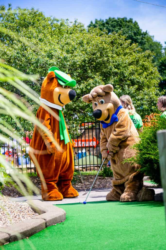 Two bear mascots playing mini golf.