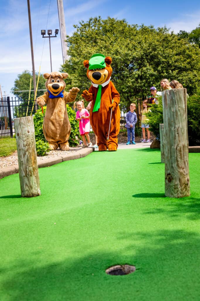 A group of teddy bears on a mini golf course.