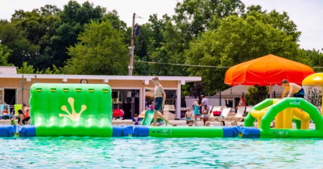 Kids playing on a giant inflatable obstacle course at a family-friendly outdoor pool in Northeast Ohio.