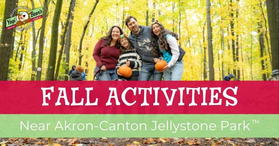 Four people stand together in a forest holding pumpkins, surrounded by fall foliage. Text reads: "Enjoy fall activities near Akron-Canton Jellystone Park.