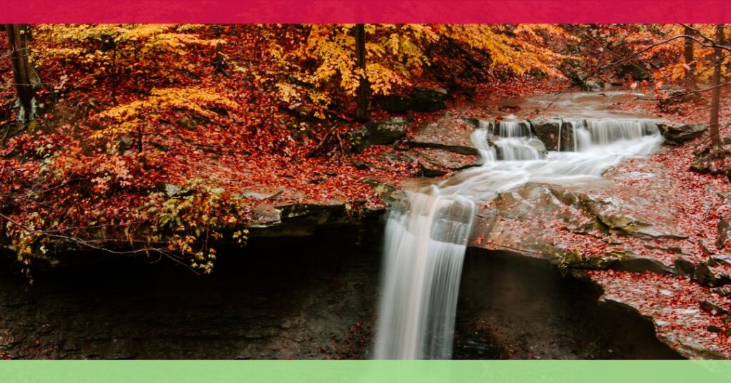 A waterfall flows over rocks surrounded by trees with vibrant autumn foliage; the image has red and green borders at the top and bottom.