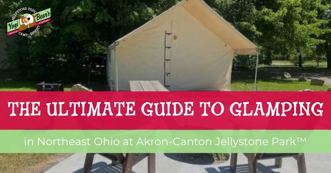 A canvas glamping tent with a picnic table and chairs outside is shown, promoting glamping at Akron-Canton Jellystone Park in Northeast Ohio.