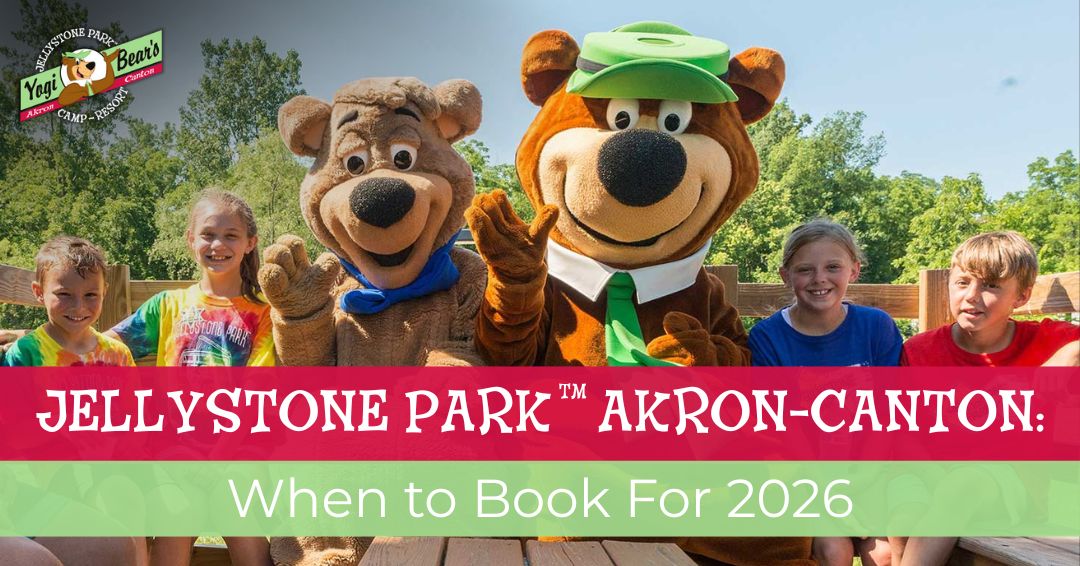 Five children sit with two people in Yogi Bear and Boo Boo bear costumes at Jellystone Park Akron-Canton, with trees and blue sky in the background. Text over the image gives booking information.