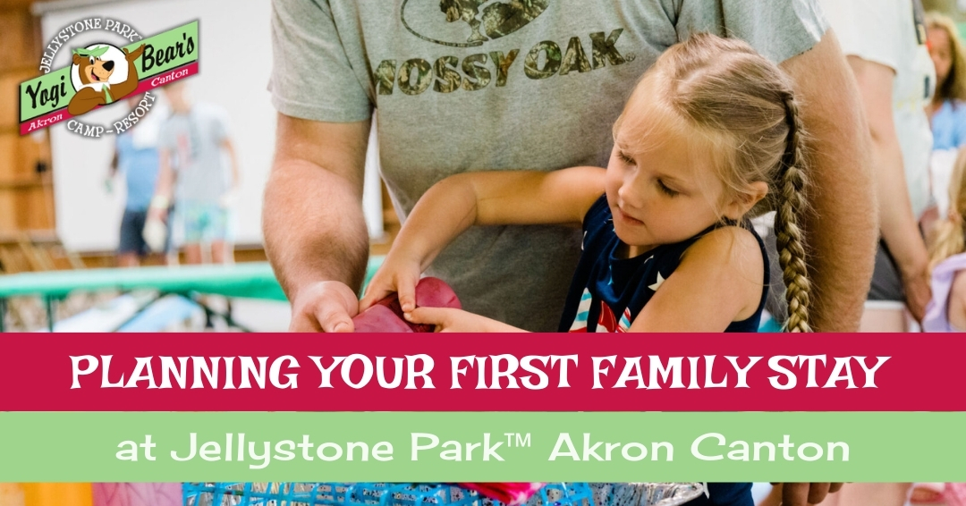 A young girl helps an adult pack a bag, with the text “Planning your first trip or family stay at Jellystone Park™ Akron Canton” overlaid on the image.